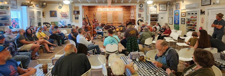 Several musicians seated in a circle playing traditional mountain music at Floyd General Store.