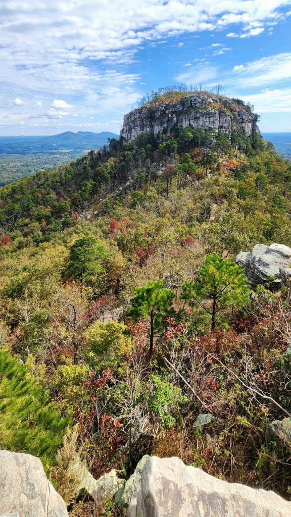 Pilot Mountain surrounded by red, orange, yellow, and green foliage.